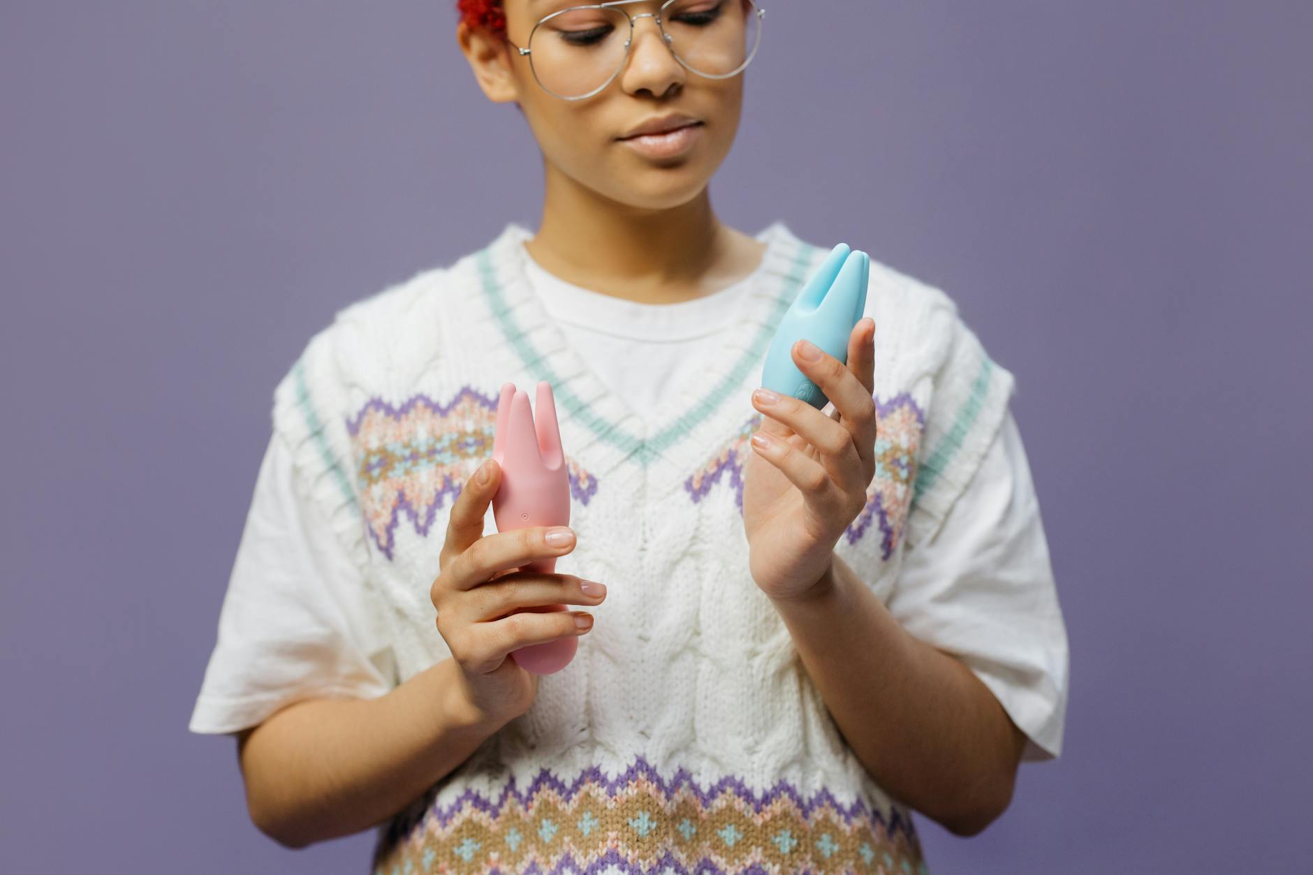 Woman holding colorful silicone vibrators contemplatively, representing openness to new pleasure tools