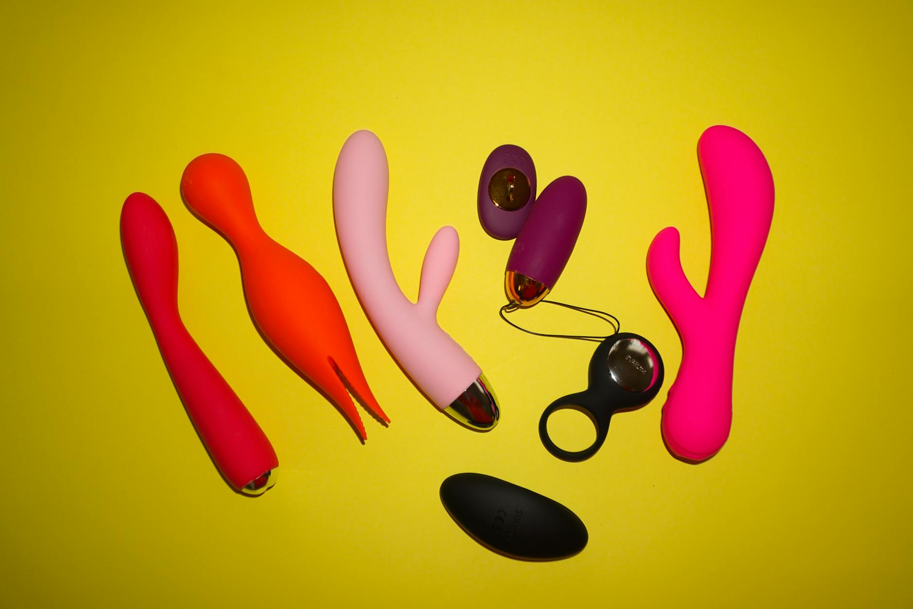 Colorful vibrators arranged on bright yellow background showing varied designs and intensity options